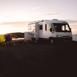 Bobil som står parkert langs en fjord. Foto.
