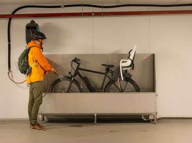 Mann står i en garasje og vasker av sykkelen etter bruk (Foto)