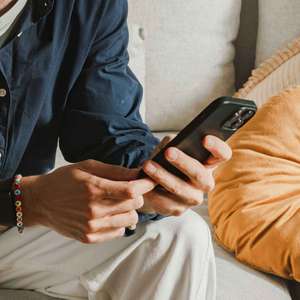 Mann sitter med mobilen i hendene (Foto)