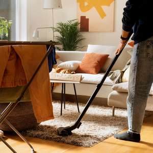 En person støvsuger et teppe i en leilighet (Foto)