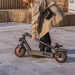 En kvinne legger sammen en el-sparkesykkel etter bruk (Foto)