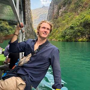 Mann lener seg ut og ser på idylliske omgivelser fra en båt i en fjord (Foto)