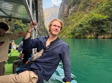 Mann lener seg ut og ser på idylliske omgivelser fra en båt i en fjord (Foto)
