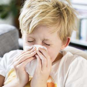 En ung gutt snyter nesen med et lommetørkle (Foto)