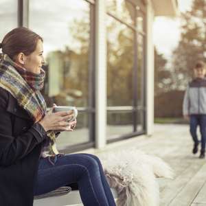 Kvinne på terasse med sønnen sin og en kopp kaffe