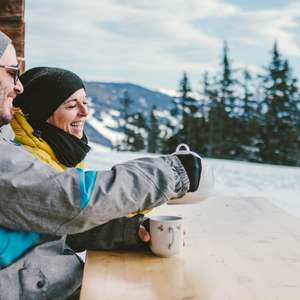 Par slapper av på en benk utenfor hytten som er forsikret i Frende