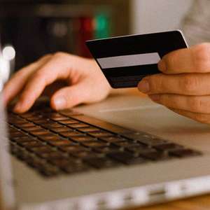 Person som skriver på tastatur og holder i et bankkort