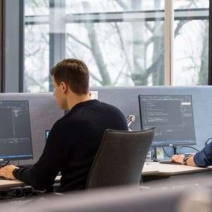 To systemutviklere sitter og arbeider på hver sin PC i Jonsvollbygget (Foto)