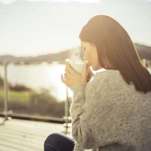 Dame drikker kaffe på terrasse