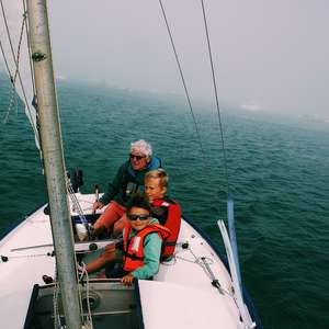 To barn med en voksen bruker redningsvest i en seilbåt på sjøen (Foto)