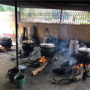 Et enkelt skolekjøkken i Ghana med flere kjeler som varmes opp av bål av store trestammer (Foto)