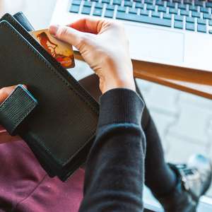 Dame med kredittkort og lommebok foran PC