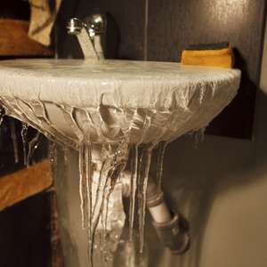 En vask som har rent over og frosset slik at det henger istapper ned