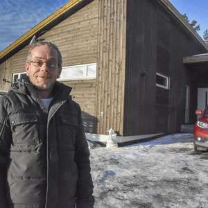 Rune Torp smiler til kamera i vinterkulden utenfor sitt nybygde hus med bilen parkert utenfor (Foto)