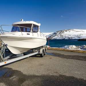 Båt står på henger på land nær sjøen (Foto)