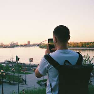 Mann tar bilde av utsikten mot en by med mobilen (Foto)