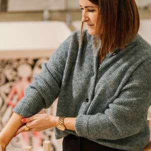 Kvinne tar seg til armen og uttrykker ubehag/smerte (Foto)