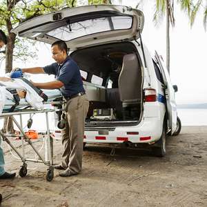 Ambulansearbeidere arbeider med en pasient på en båre på en strand i varme strøk (Foto)