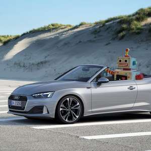 En morsom robot sitter i førersetet av en cabriolet på en parkeringsplass (Foto)