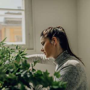 En kvinne beskjærer planter ved et vindu (Foto)